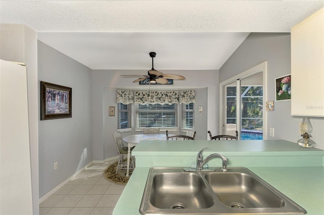 kitchen with ceiling fan, sink, white fridge, vaulted ceiling, and light tile patterned floors