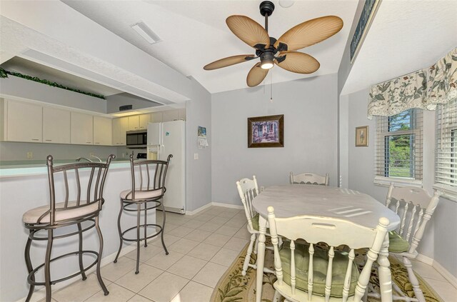 tiled dining room featuring ceiling fan and vaulted ceiling