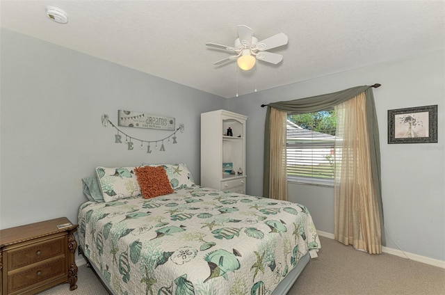 carpeted bedroom featuring ceiling fan and a textured ceiling