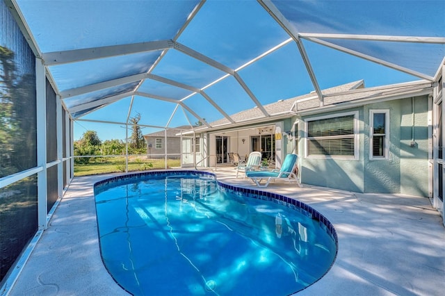 view of pool featuring glass enclosure and a patio