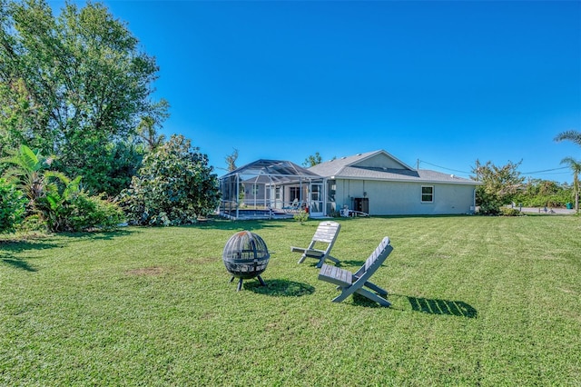 view of yard featuring a lanai and an outdoor fire pit