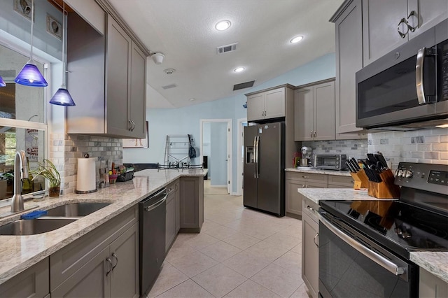 kitchen featuring tasteful backsplash, stainless steel appliances, vaulted ceiling, sink, and decorative light fixtures