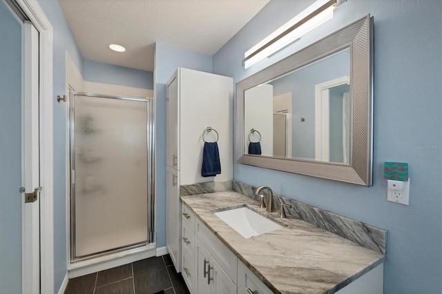 bathroom featuring a textured ceiling, vanity, and walk in shower