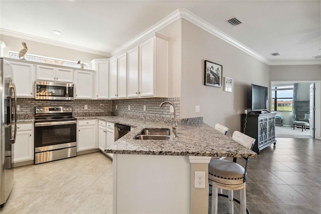 kitchen featuring white cabinets, sink, a kitchen bar, kitchen peninsula, and stainless steel appliances