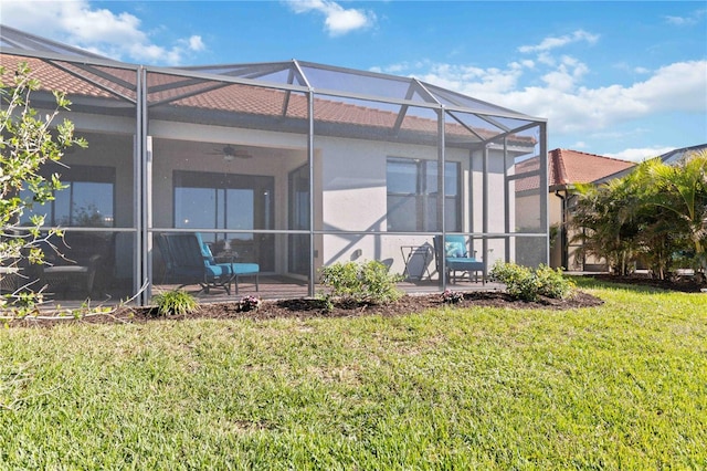 back of house with ceiling fan, a yard, a patio, and glass enclosure