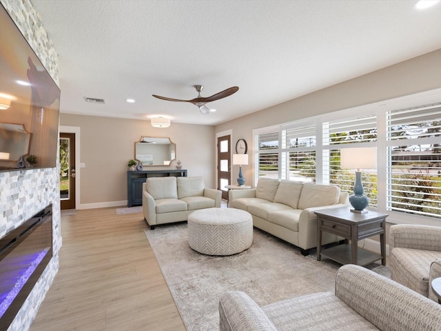 living room featuring a textured ceiling, light hardwood / wood-style floors, and ceiling fan