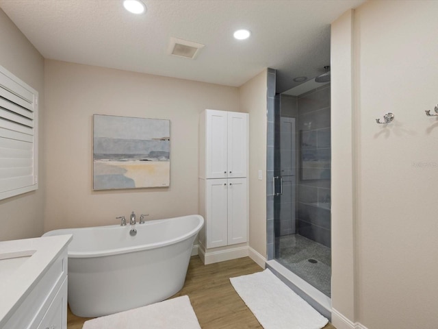 bathroom with separate shower and tub, hardwood / wood-style floors, vanity, and a textured ceiling