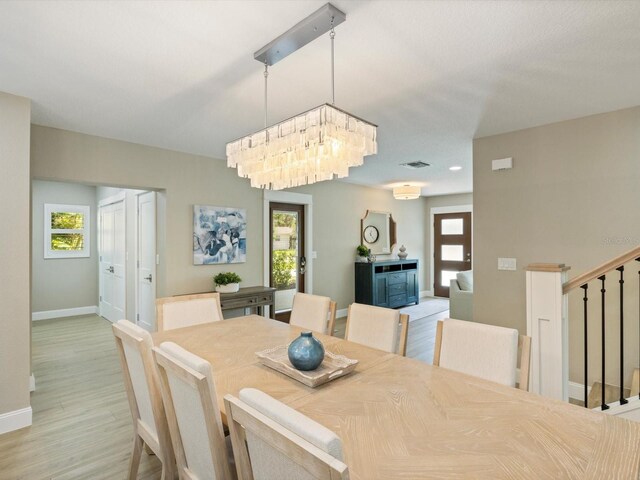 dining area with an inviting chandelier and light hardwood / wood-style flooring