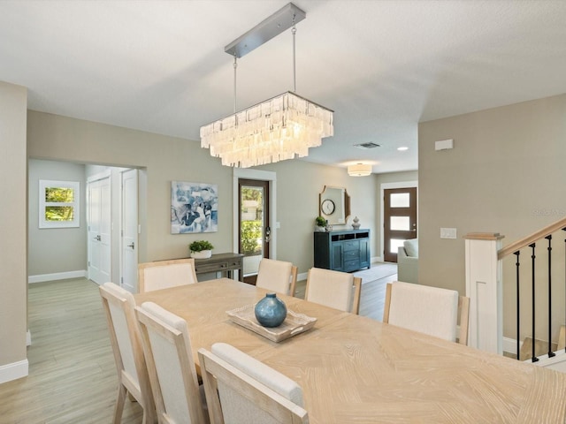 842 Nokomis Ave S, Venice, FL 34285 - dining area with light wood-style flooring, baseboards, stairs, and a chandelier