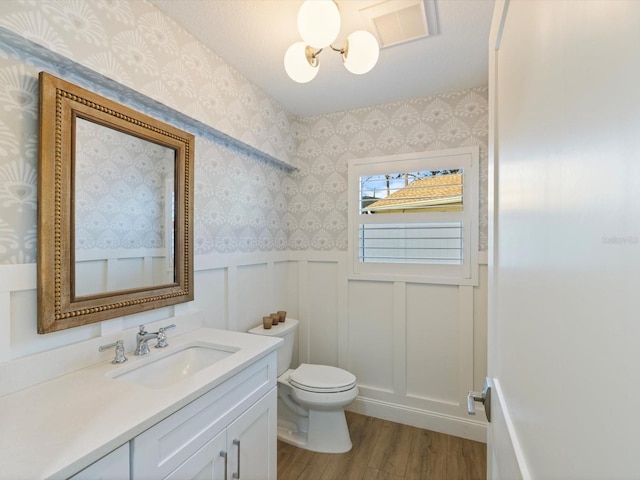 bathroom with hardwood / wood-style floors, vanity, toilet, and an inviting chandelier