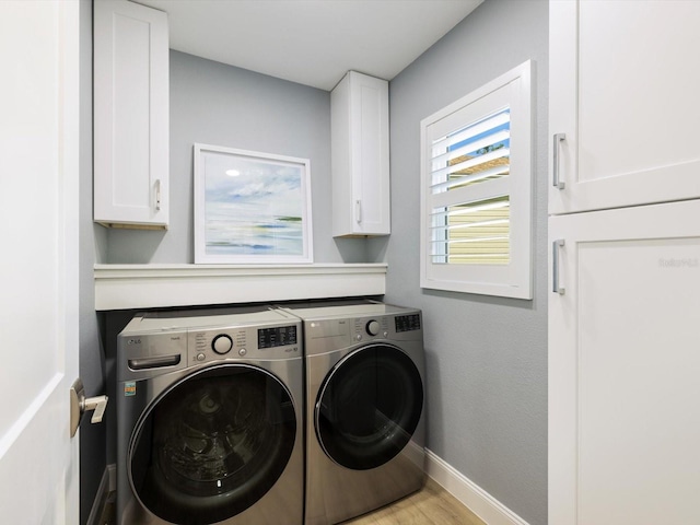 clothes washing area featuring cabinets, light wood-type flooring, and separate washer and dryer