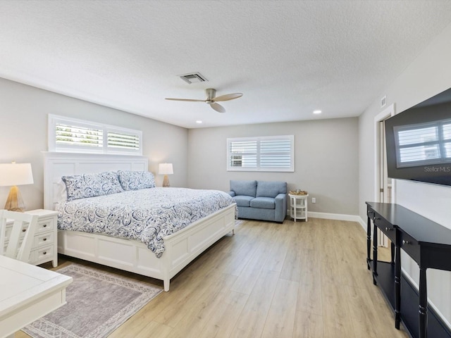 bedroom with ceiling fan, light wood-type flooring, and a textured ceiling