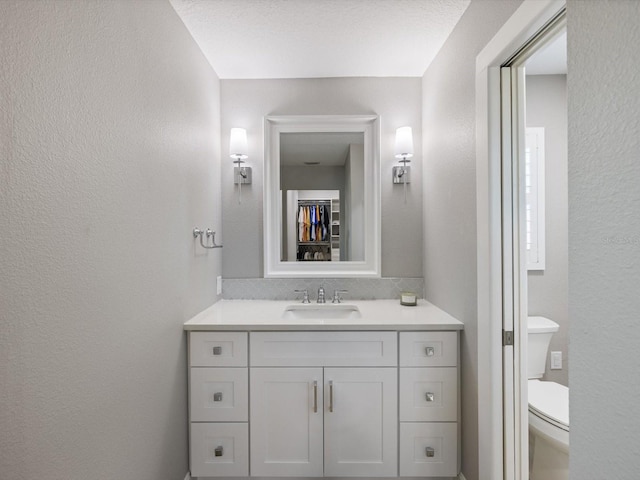 bathroom with a textured ceiling, vanity, and toilet