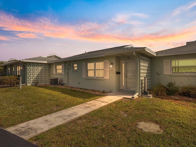 view of front of property with a lawn and central air condition unit