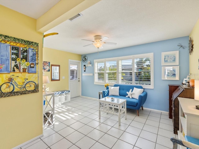 living area with ceiling fan, light tile patterned floors, and a textured ceiling