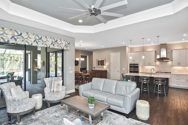 living room featuring dark hardwood / wood-style floors, a raised ceiling, and ornamental molding