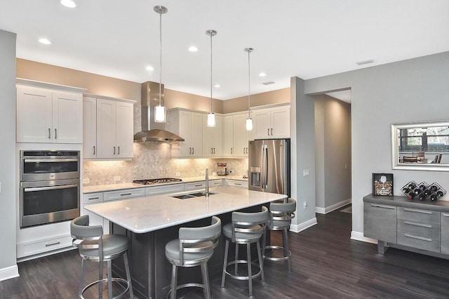 kitchen with white cabinetry, sink, wall chimney exhaust hood, stainless steel appliances, and pendant lighting