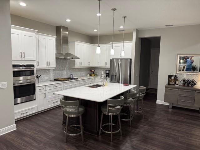 kitchen with white cabinets, stainless steel appliances, and wall chimney exhaust hood