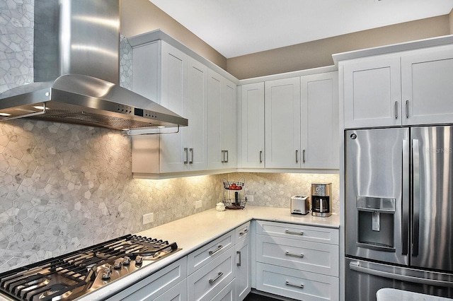 kitchen featuring tasteful backsplash, white cabinetry, wall chimney exhaust hood, and stainless steel appliances