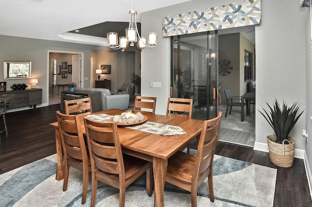 dining space with dark wood-type flooring and a chandelier