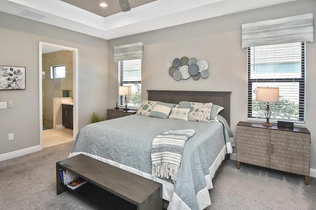 carpeted bedroom with ensuite bathroom, multiple windows, and ceiling fan