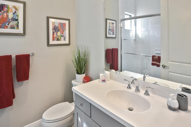 bathroom featuring vanity, toilet, and a shower with shower door