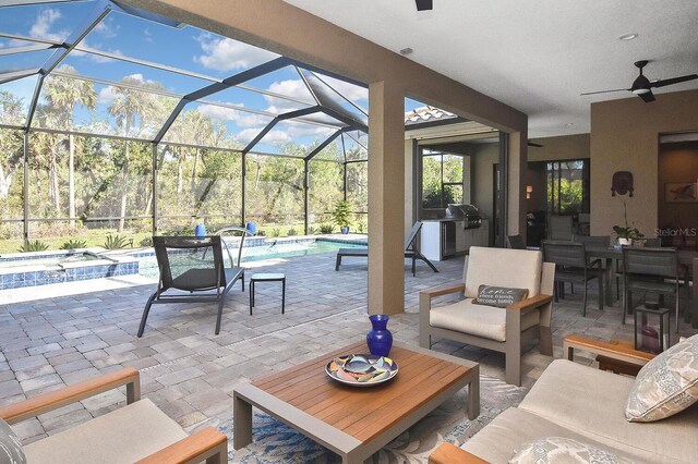 view of patio / terrace featuring outdoor lounge area, glass enclosure, a pool with hot tub, ceiling fan, and a grill