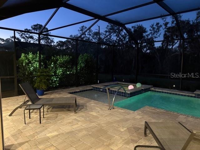 view of swimming pool featuring an in ground hot tub, a patio, and a lanai