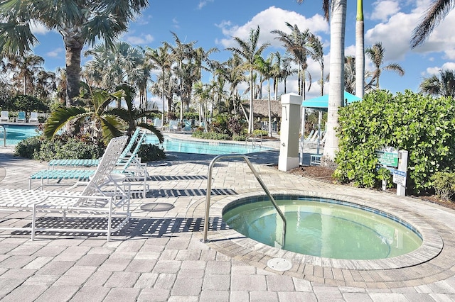 view of swimming pool featuring a patio and a hot tub