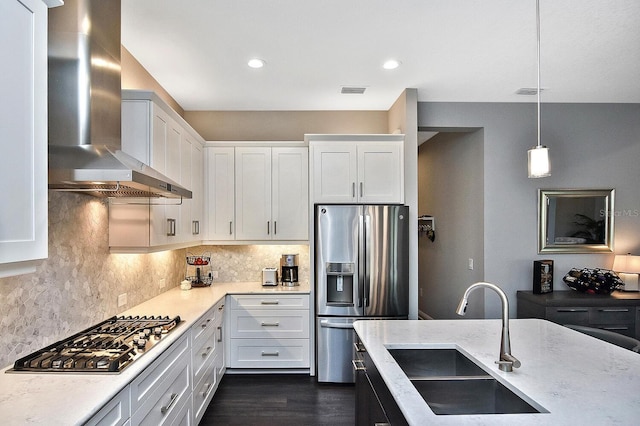 169 N Cayman Isles Blvd, Englewood, FL 34223 - kitchen with wall chimney range hood, appliances with stainless steel finishes, a sink, tasteful backsplash, and light stone countertops
