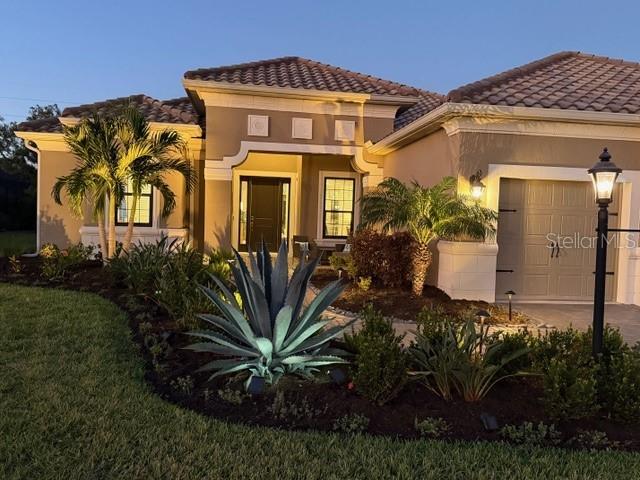169 N Cayman Isles Blvd, Englewood, FL 34223 - mediterranean / spanish house with a garage, stucco siding, and a tiled roof