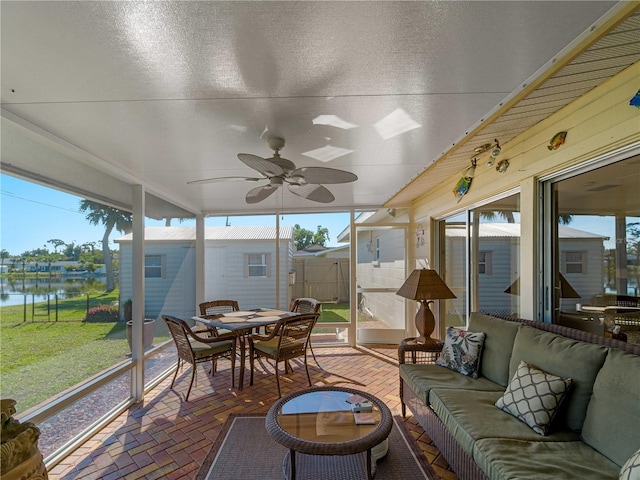 sunroom / solarium featuring a water view, plenty of natural light, and ceiling fan