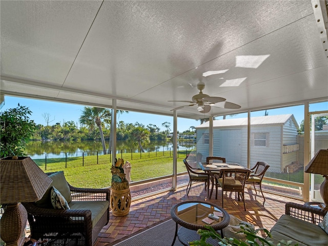 sunroom with ceiling fan and a water view