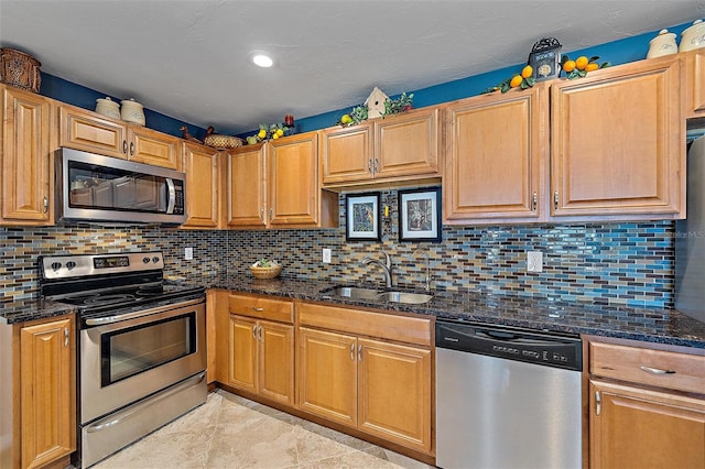 kitchen featuring sink, stainless steel appliances, backsplash, dark stone countertops, and light tile patterned flooring