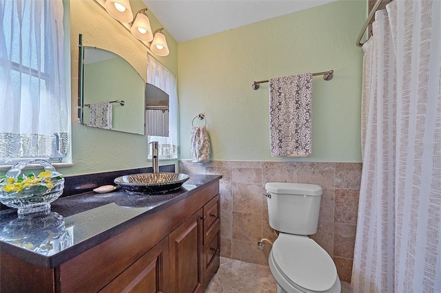 bathroom featuring tile patterned floors, vanity, toilet, and tile walls