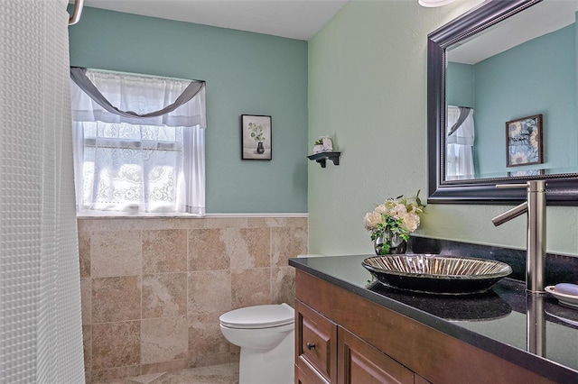 bathroom featuring curtained shower, vanity, tile walls, and toilet