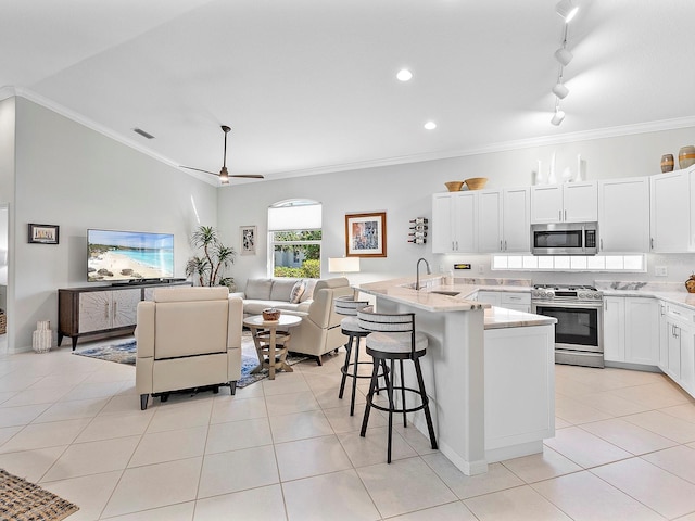 kitchen featuring ornamental molding, stainless steel appliances, sink, a center island with sink, and white cabinets