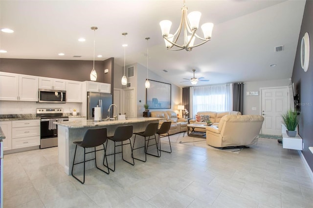 kitchen with appliances with stainless steel finishes, a kitchen breakfast bar, ceiling fan with notable chandelier, white cabinets, and hanging light fixtures