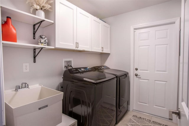 washroom with washing machine and clothes dryer, sink, and cabinets