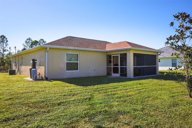 back of house featuring a lawn, a sunroom, and central AC unit