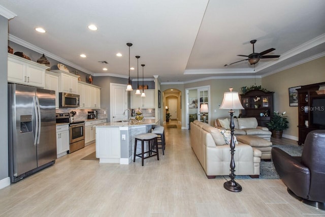 interior space with stainless steel appliances, sink, pendant lighting, a center island with sink, and a breakfast bar area