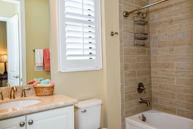 full bathroom featuring tiled shower / bath combo, toilet, and vanity