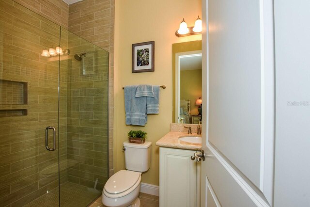 bathroom featuring tile patterned floors, a shower with door, vanity, and toilet