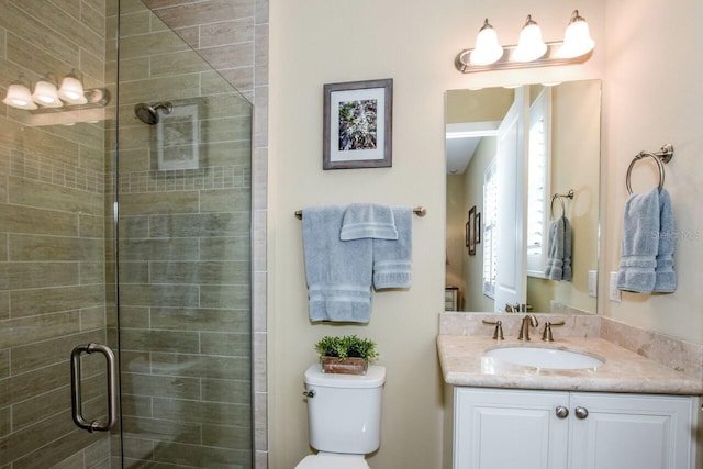 bathroom featuring vanity, a shower with shower door, and toilet