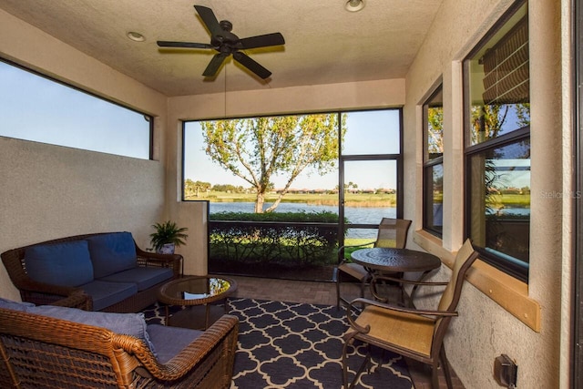 sunroom / solarium featuring ceiling fan and a water view