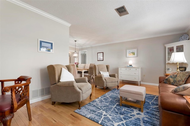 living room with light hardwood / wood-style floors, crown molding, and a textured ceiling