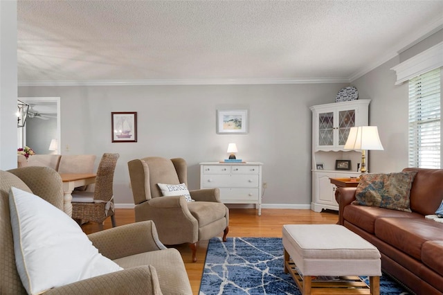 living room with crown molding, ceiling fan, a textured ceiling, and light wood-type flooring