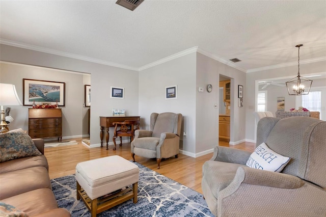 living room featuring a textured ceiling, light wood-type flooring, crown molding, and a chandelier