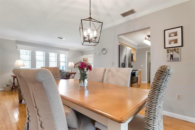 dining area featuring a textured ceiling, light hardwood / wood-style floors, crown molding, and a chandelier