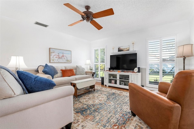 living room featuring wood-type flooring, a textured ceiling, a wealth of natural light, and ceiling fan